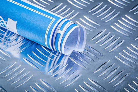 Blue rolled blueprints on corrugated metal background construction concept