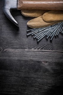 Working gloves construction nails claw hammer on vintage wooden board