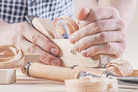 Woodworkers plane in hands of carpenter very close up
