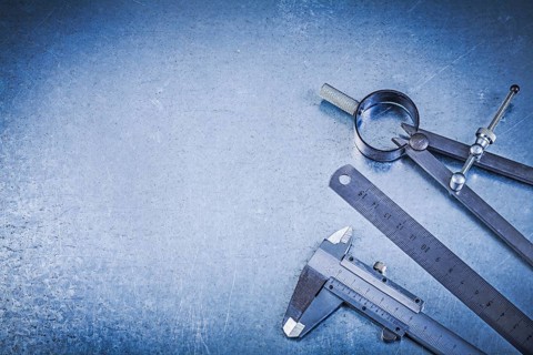 Metal construction drawing compass ruler caliper on metallic background