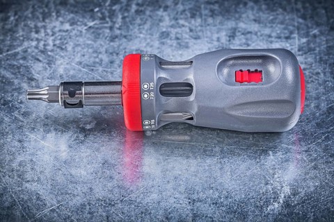 Screwdriver with replaceable bits on metallic background construction concept