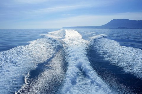 Fishing speedy boat prop wash, white wake on the blue ocean sea