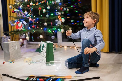 Happy boy opening a Christmas gift and Christmas tree in the background