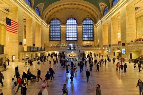 People moving through a large railway station concourse under a cool glow of light, Manhattan,