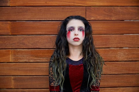 Halloween kid girl custome with bloody makeup on wooden wall
