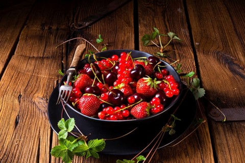 Bowl with different fruits such as strawberry, red currant, and cherry