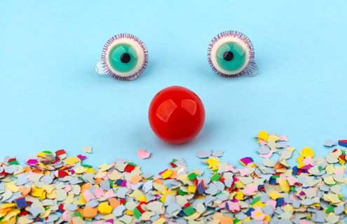 Red Nose with confetti over light blue background. Conceptual Photo to use for all funny