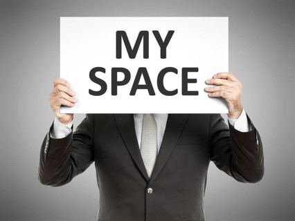 A business man holding a paper in front of his face with the message my space