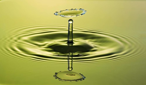 Gravity Dancing drop of water on a green background