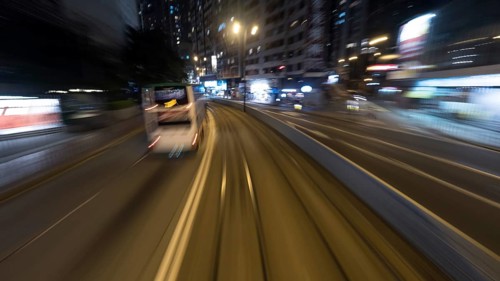 Traveling through the night city by double-decker tram. View to the rails and transport on the road