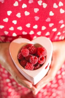 Woman in red dress holding a cup of raspberries