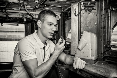 Black and White Retro Close Up of Young Man Speaking into Handheld Radio in Engine of Old Fashioned