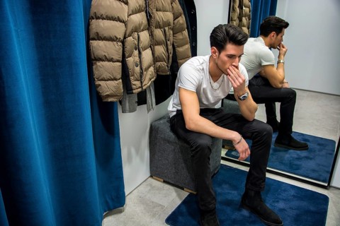 Young Handsome Man Trying on Clothes in Clothing Store's Changing Room in Front of a Mirror or in