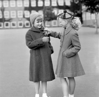 Girls in the 1950s. Two teenage girls dressed in outfits typical of the decade. Both in warm coats