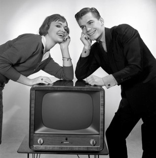 Television in the 1950s. A young couple is pictured beside a typical 50s television set. Photo