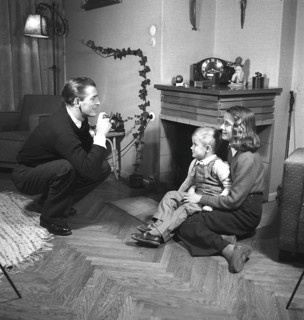 Amateur photographer in the 1940s A man is taking pictures of his wife and son at home. He is