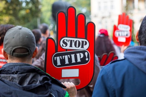 Activists are holding red hand signs Stop TTIP during a demonstration against Free Trade Agreements