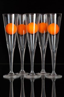 Five glasses of champagne and orange golf balls on the glass plate