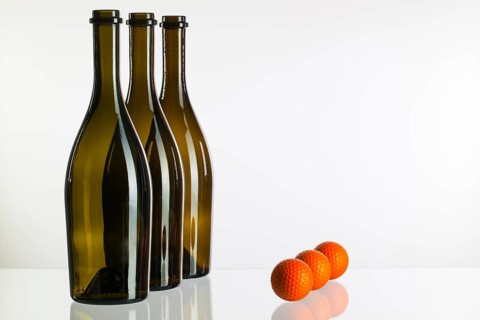 Empty three wine bottles and golf balls on a glass desk