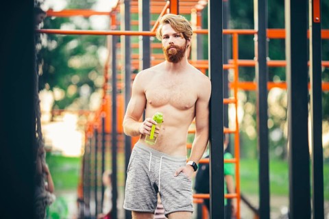 Thirst and health. Sportsman hold water bottle on stadium. Fit man with plastic flask outdoor. Stay
