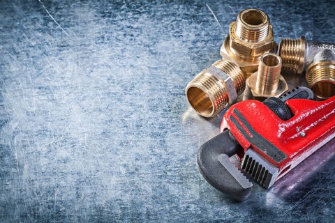 Monkey wrench brass nipple hose connectors on metallic background plumbing concept