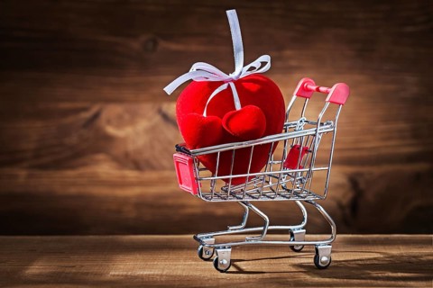 Red heart toy in shopping cart on vintage wood