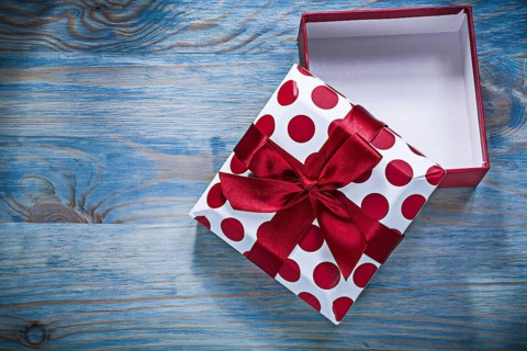 Red gift box with tied bow on wooden board holidays concept