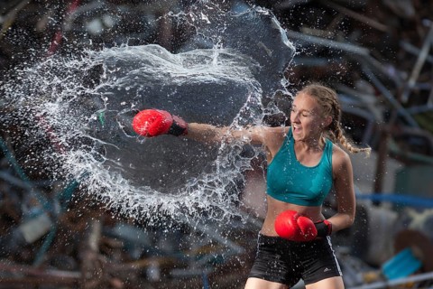 Boxer hits water balloon powerfully, proof of strength and determination, staged photo shoot,