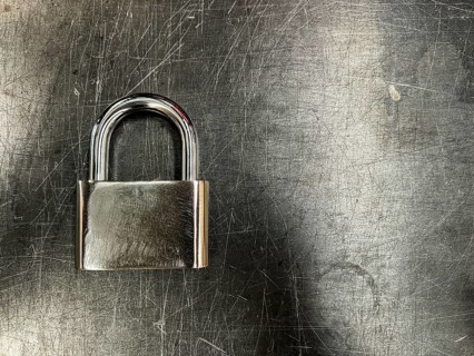 Metallic padlock on metal texture background