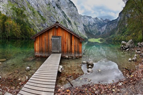 Cloudy day at Lake Koenigssee. Boathouse connected to the coast wooden decking. Clouds and