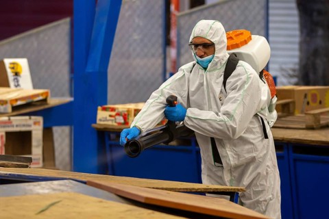 Sofia, Bulgaria - 7 April, 2020: Worker sprays disinfectant outside of ? food market against the