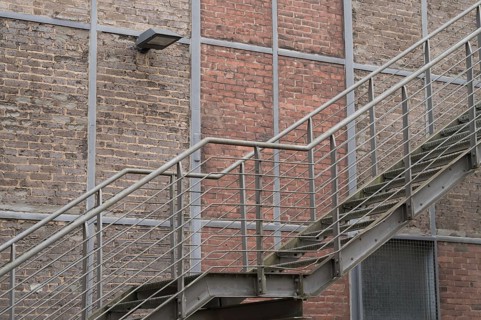 Metal fire escape climbing a brick wall with a lamp