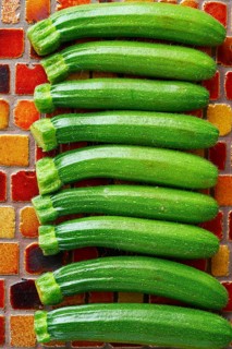 Mini zucchini vegetables in a row on red brown tiles table