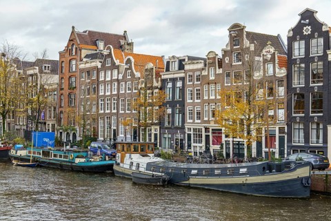 Row of stately buildings along the canal as autumn colours the trees, Amsterdam, Netherlands