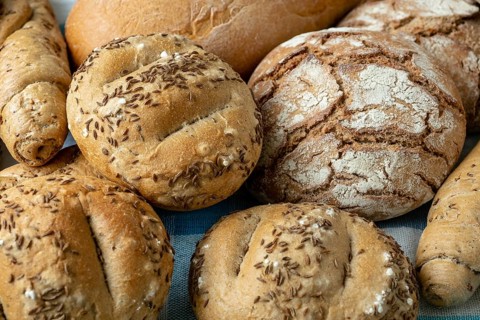 Heap of various bread rolls sprinkled with salt, caraway and sesame. Fresh rustic bread from