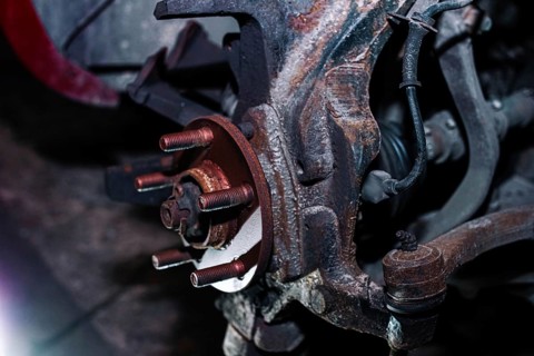 Rusty vehicle brake disc mount without the disc attached in a dim workshop setting