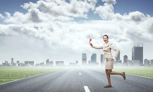 Woman running outdoor with vintage red phone. Expressive secretary with telephone on background