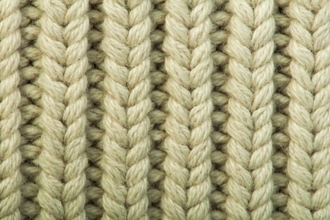 Old knit sweater background. Beige color. Studio shot