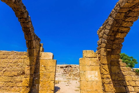 Ruins of ancient Caesarea against the background of the blue southern sky. Excursion to the