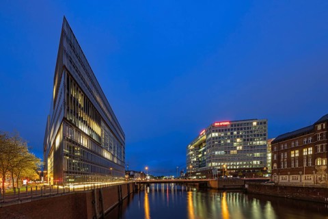Modern office buildings reflect in the water at night, illuminated by numerous lights, Blue Hour,