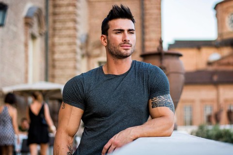 Attractaive muscular man with tattoo posing in European city center, Turin, Italy, looking at