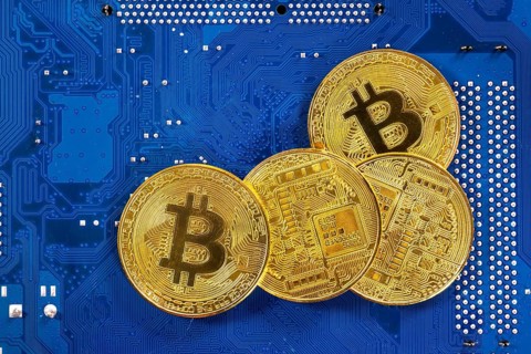 Virtual cryptocurrency money Bitcoin golden coins on a computer printed circuit board PCB. The