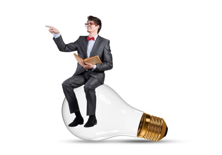 Young businessman sits on an electric light bulb. holds a book in his hands