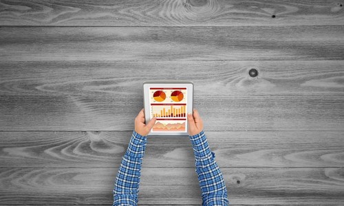 Top view of girl hands using tablet pc with diagrams and graphs on screen