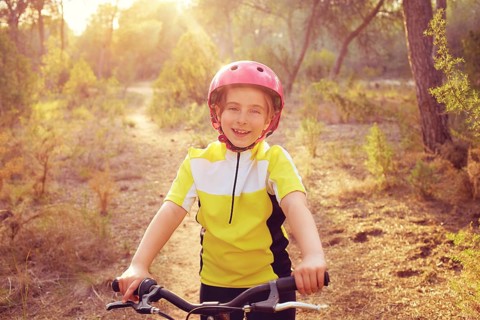 Kid girl biker in mountain bike MTB at mediterranean forest