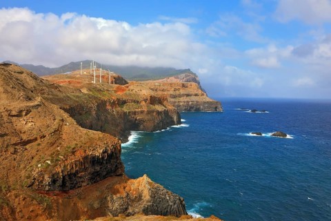 Eastern tip of the island of Madeira. Rocks steeply in the blue waters of the Atlantic Ocean. Over