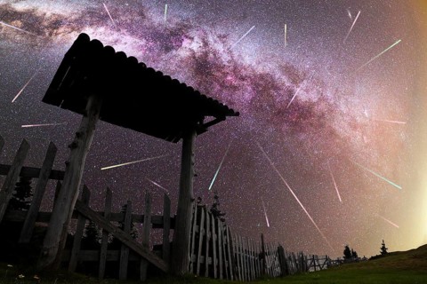 A view of a Meteor Shower and the purple Milky Way with wooden entrance door with a roof and fence