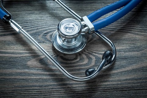 Medical stethoscope on wooden board top view