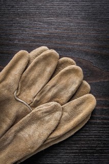 Leather working gloves on vintage wooden board vertical version construction concept
