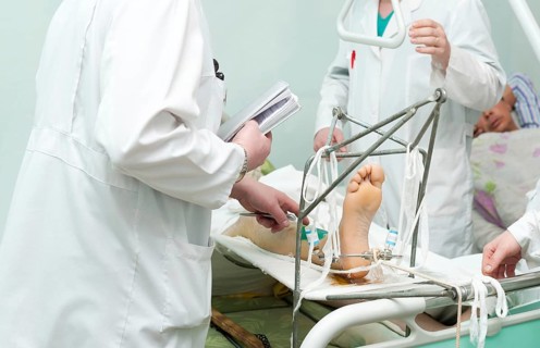 Group of surgeons examine patient with broken leg
